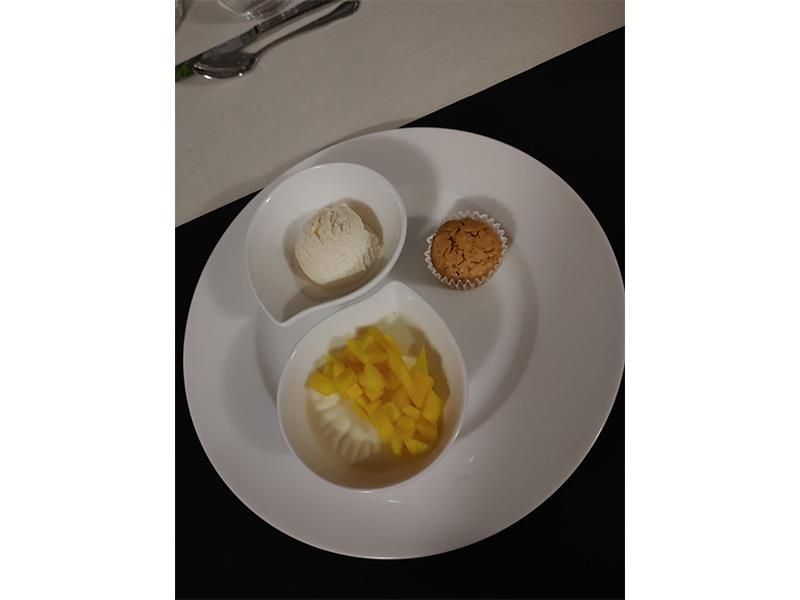 Ein weißer Teller mit zwei Schüsseln mit Essen und einem Muffin.