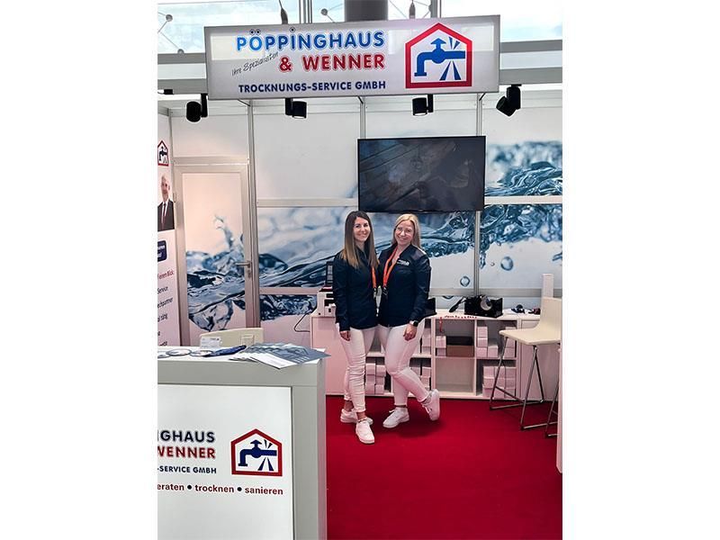 Zwei Frauen stehen vor einem Schild mit der Aufschrift Poppinghaus & Wenner