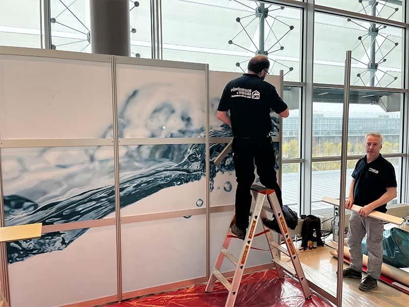 Ein Mann steht auf einer Leiter, während ein anderer Mann zusieht