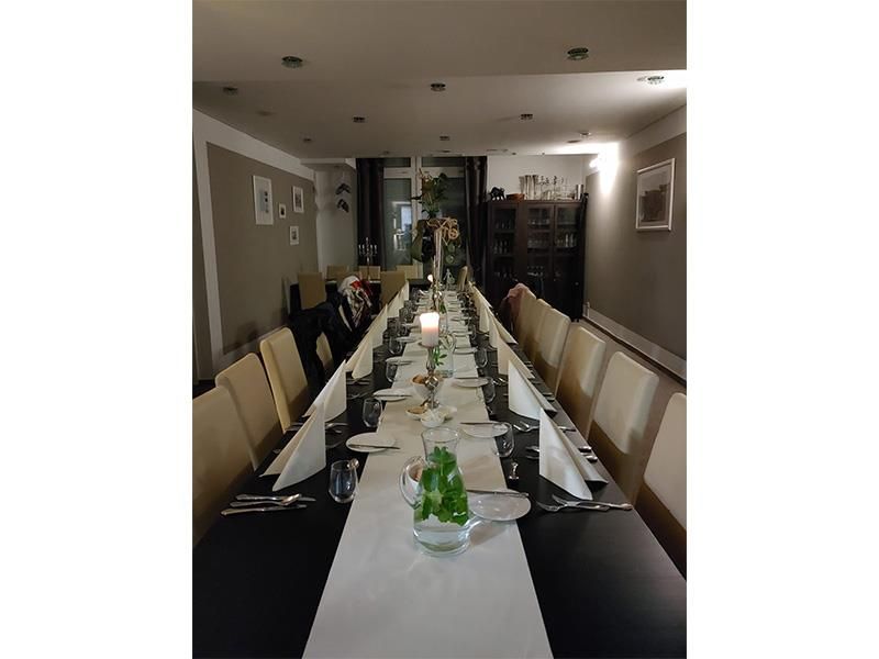 In einem Restaurant ist ein langer Tisch für eine Dinnerparty gedeckt.