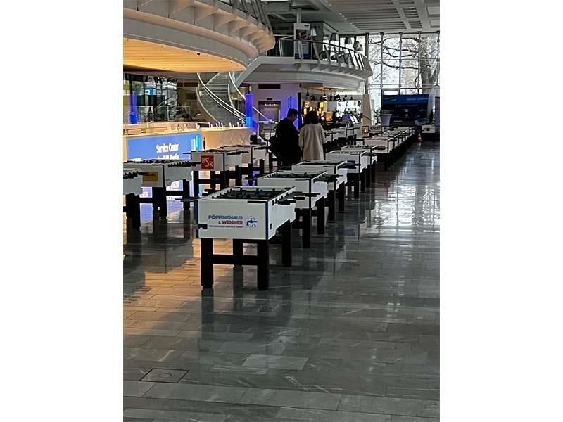 In einem großen Raum stehen mehrere Tische in einer Reihe.