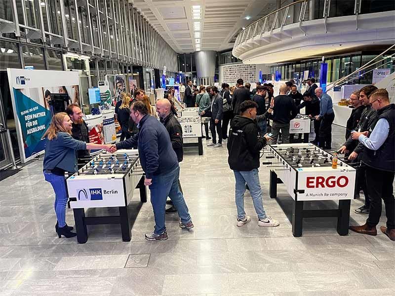 Eine Gruppe von Leuten spielt in einem großen Raum Tischfußball.