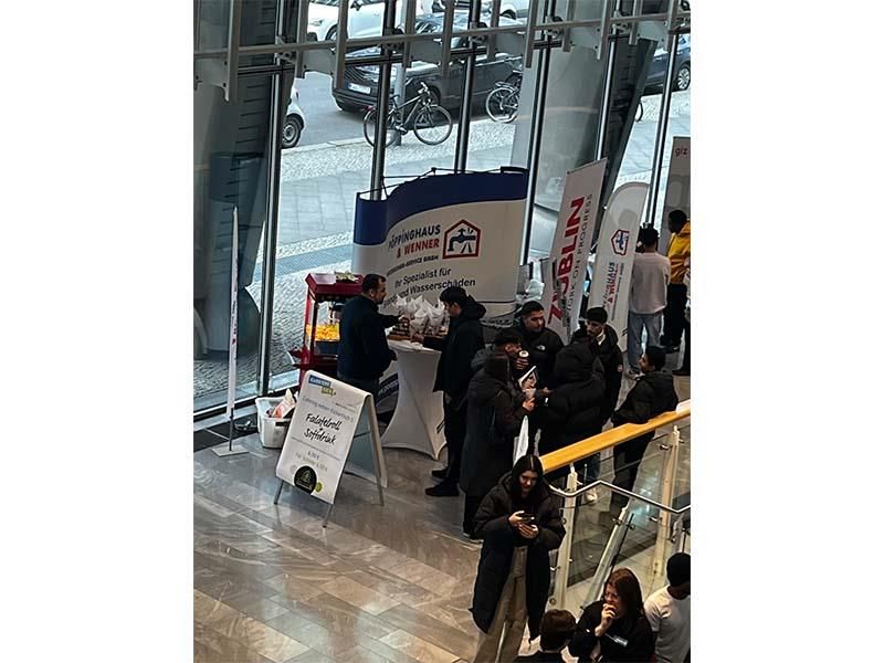 Eine Gruppe von Leuten steht in einem Gebäude um einen Tisch herum.