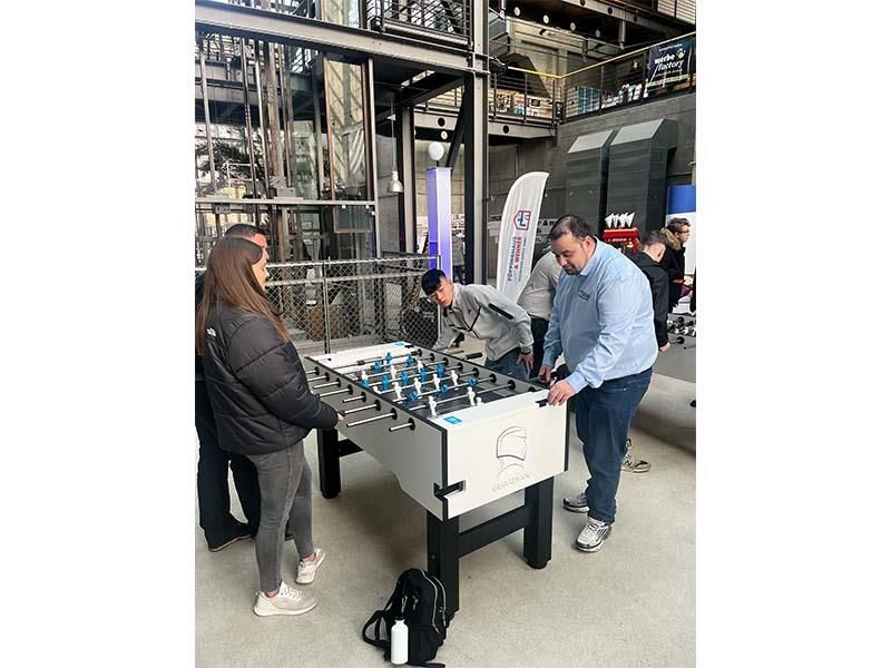 Eine Gruppe von Leuten spielt in einem Raum Tischfußball.