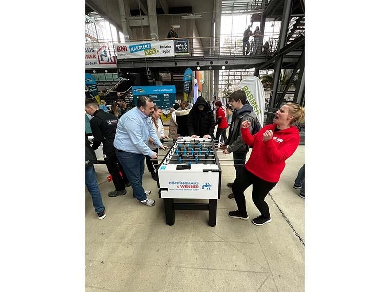 Eine Gruppe von Leuten steht um einen Tischfußballtisch herum.
