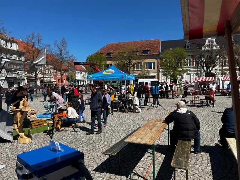 Eine große Gruppe von Menschen versammelt sich auf einem kleinen Stadtplatz