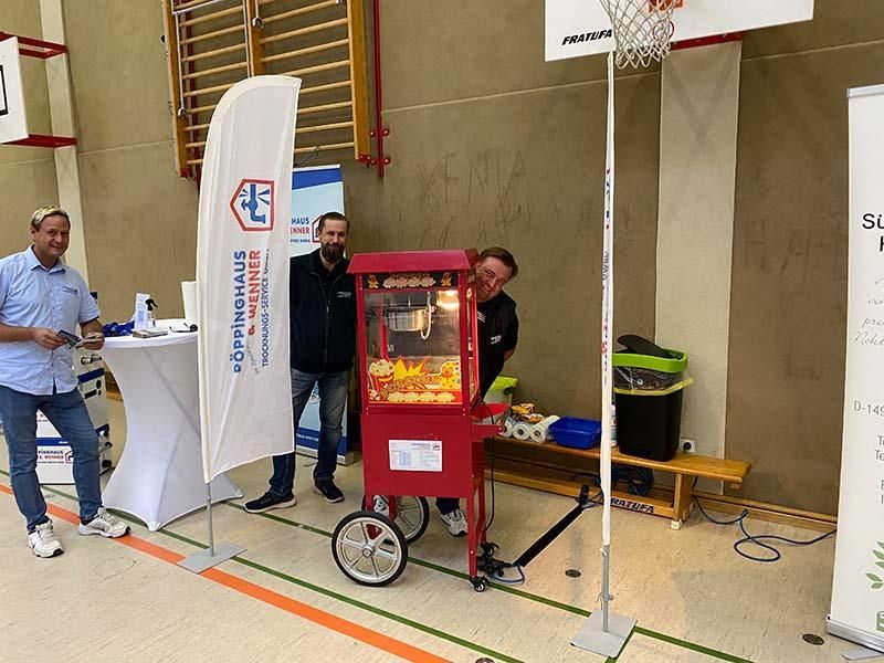 Eine Gruppe von Männern steht um eine Popcornmaschine in einem Fitnessstudio