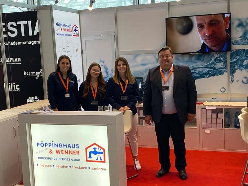 Eine Gruppe von Menschen steht vor einem Poppinghaus-Schild