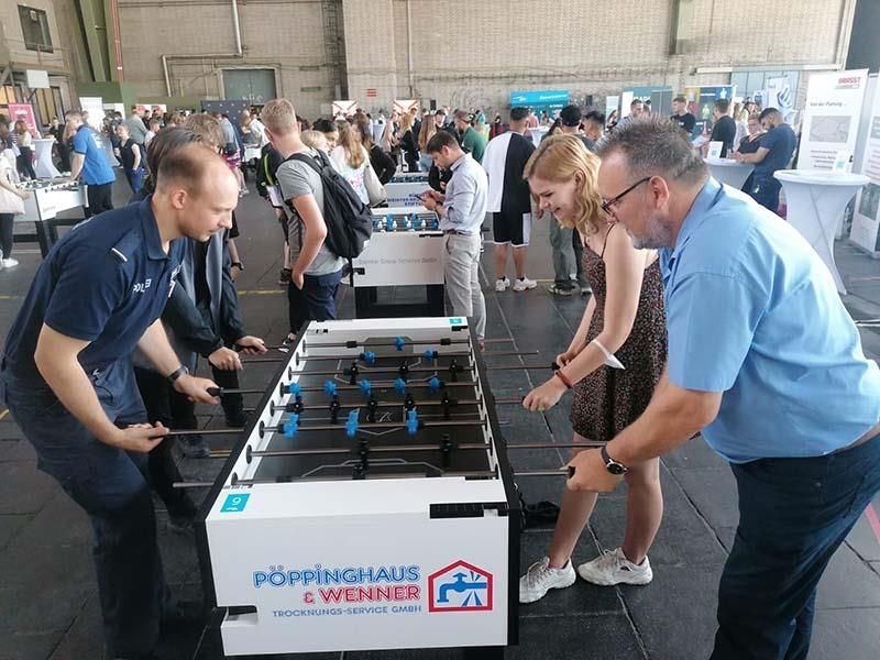 Eine Gruppe von Leuten steht um einen Tischfußballtisch herum.