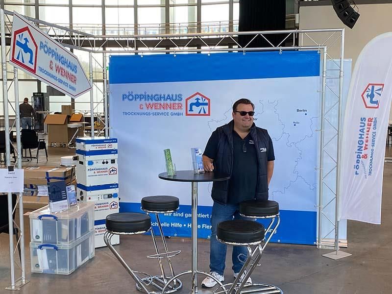 Ein Mann steht an einem Tisch vor einem Schild mit der Aufschrift „Domhaus“