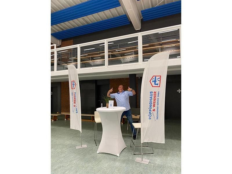 Ein Mann steht vor einem Tisch mit einer Fahne, auf der 