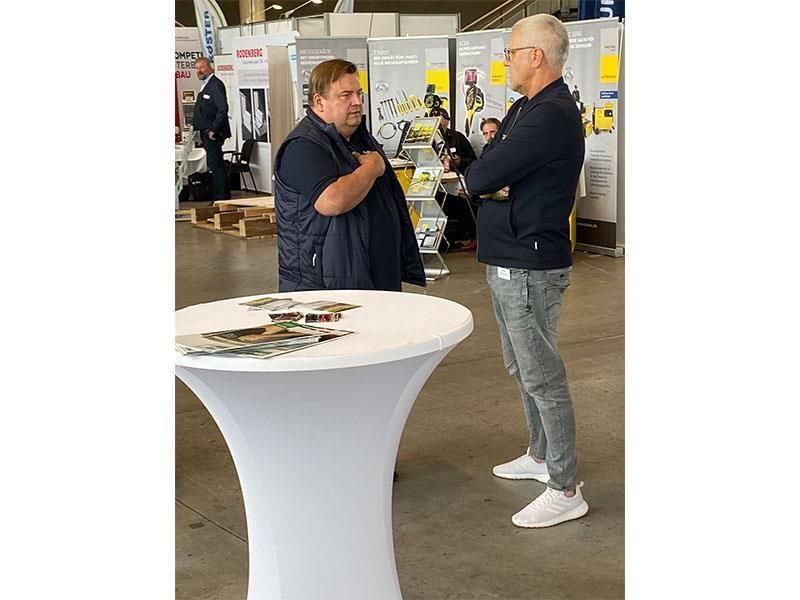 Zwei Männer stehen vor einem Tisch und unterhalten sich.