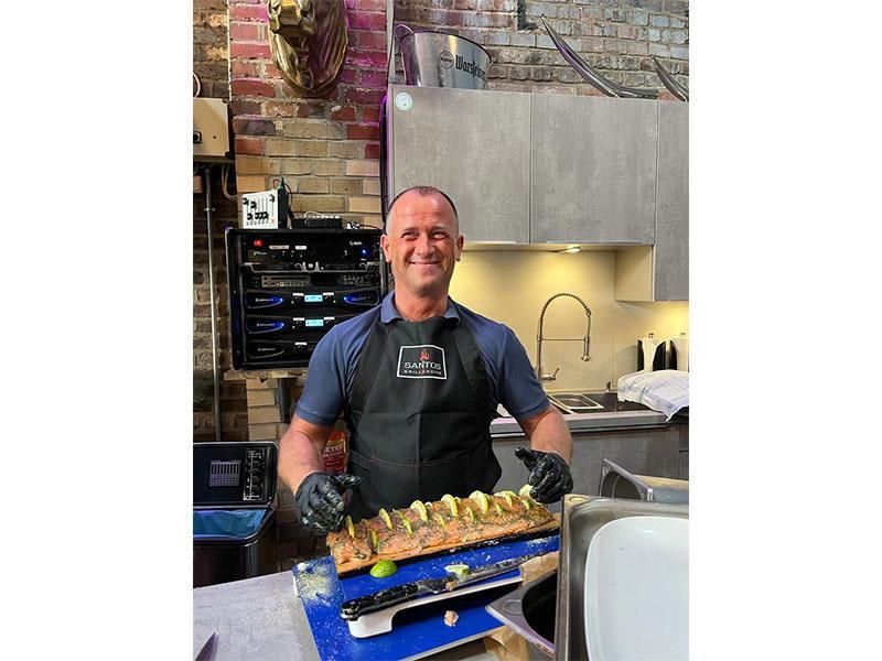 Ein Mann in einer Schürze steht in einer Küche und hält ein Stück Fleisch.