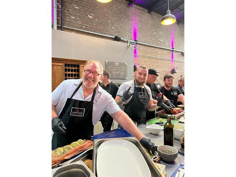 Eine Gruppe Männer steht um einen Tisch und bereitet Essen zu.