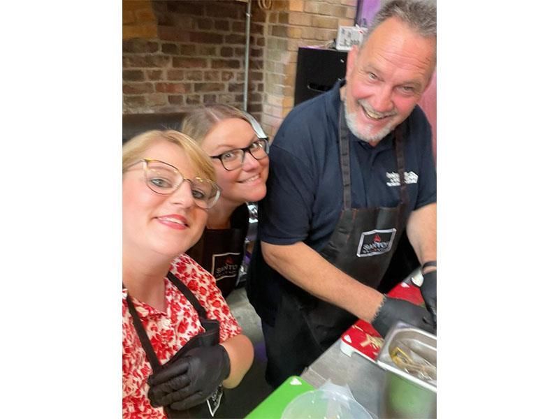 Ein Mann und zwei Frauen stehen nebeneinander in einer Küche.