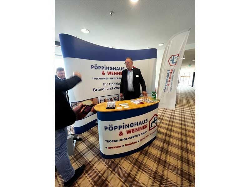 Ein Mann steht hinter einem Tisch mit der Aufschrift „Poppinghaus“