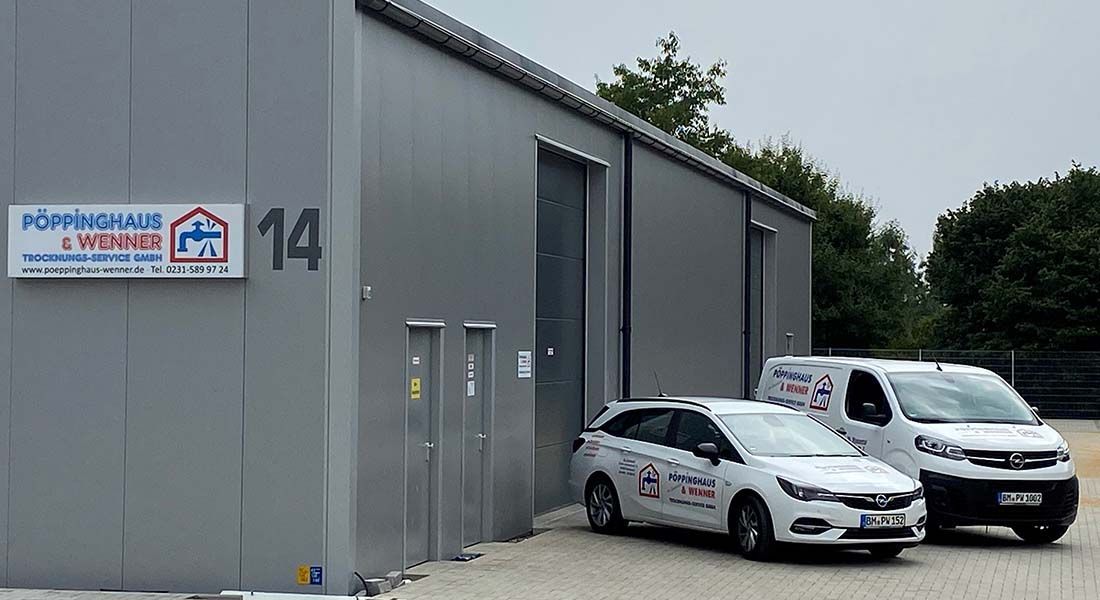 Drei weiße Lieferwagen stehen vor einem Gebäude mit einem Schild mit der Aufschrift „14“