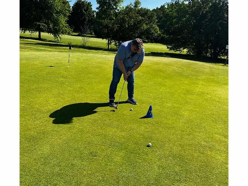 Ein Mann spielt Golf auf einem üppigen grünen Feld.