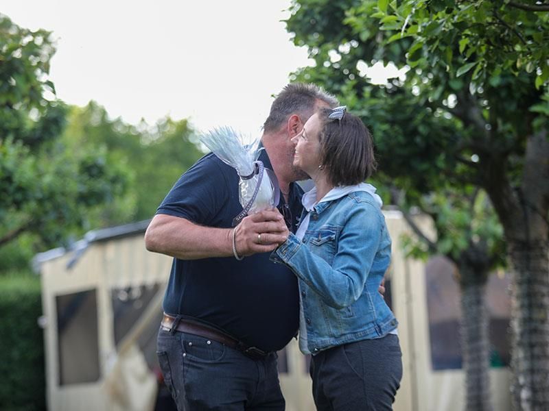 Ein Mann und eine Frau küssen sich vor einem Zelt.