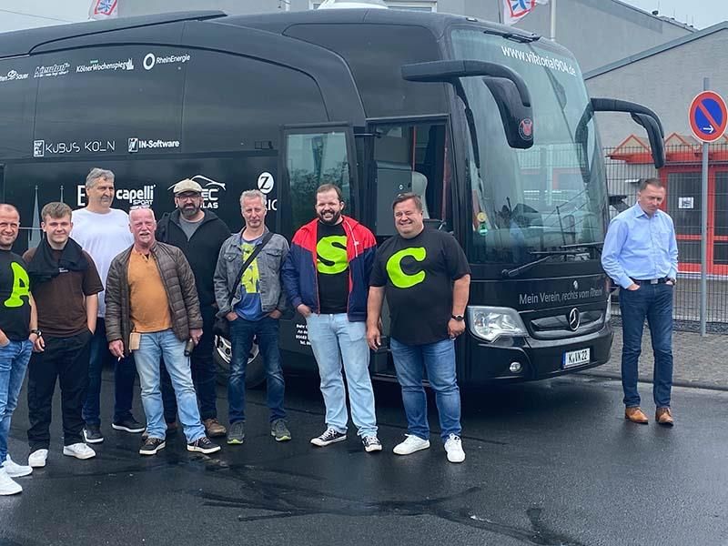 Eine Gruppe Männer posiert vor einem Bus für ein Foto.