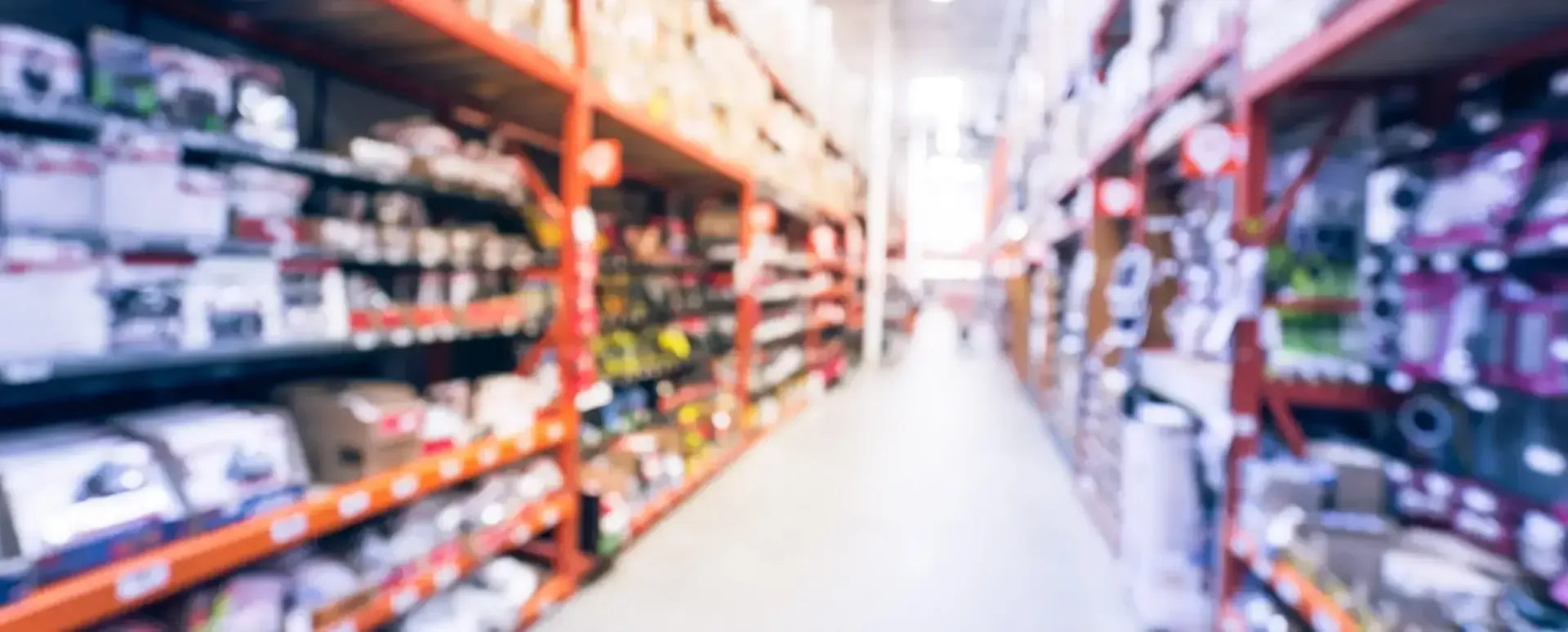 Vista borrosa de un pasillo de una tienda con estantes llenos de productos. Iluminación cálida.