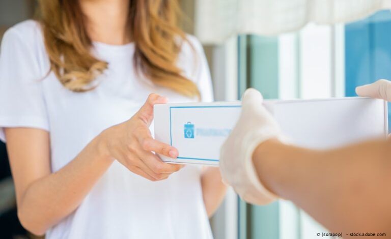 Eine Person übergibt einer anderen Person in einem hellen Innenraum einen verpackten Gegenstand.