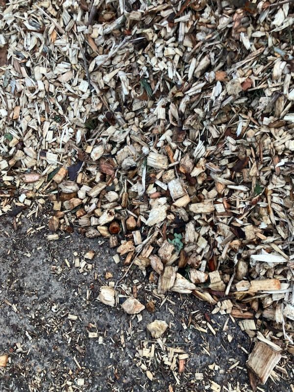 Un tas de copeaux de bois et de paillis d'écorce à côté d'une surface pavée sombre
