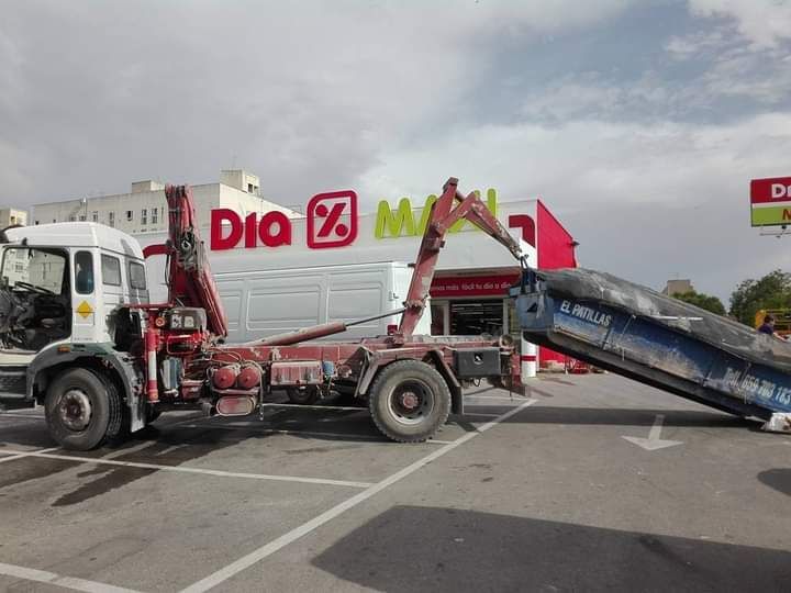 Un camión volquete está estacionado frente a un edificio que dice