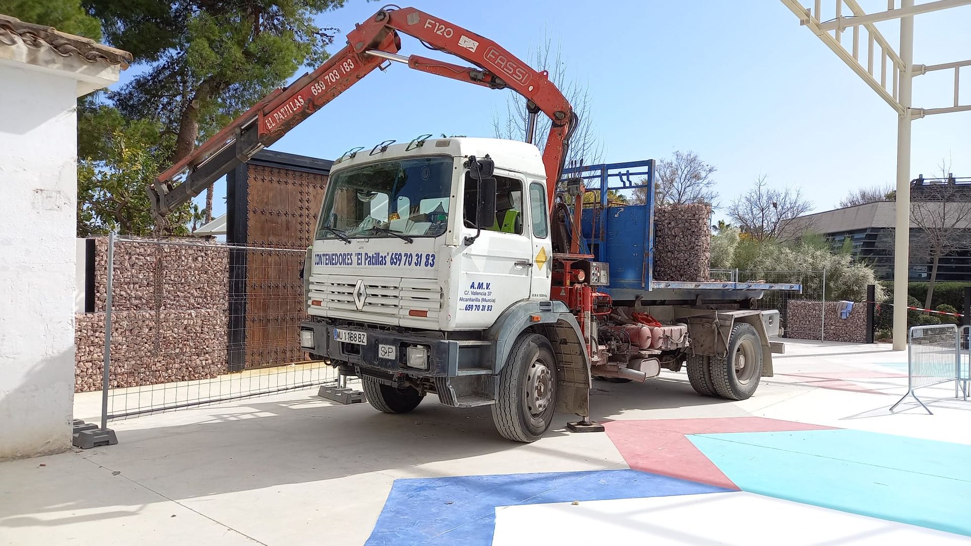 Un camión blanco con una grúa roja en la parte trasera está estacionado en un estacionamiento.