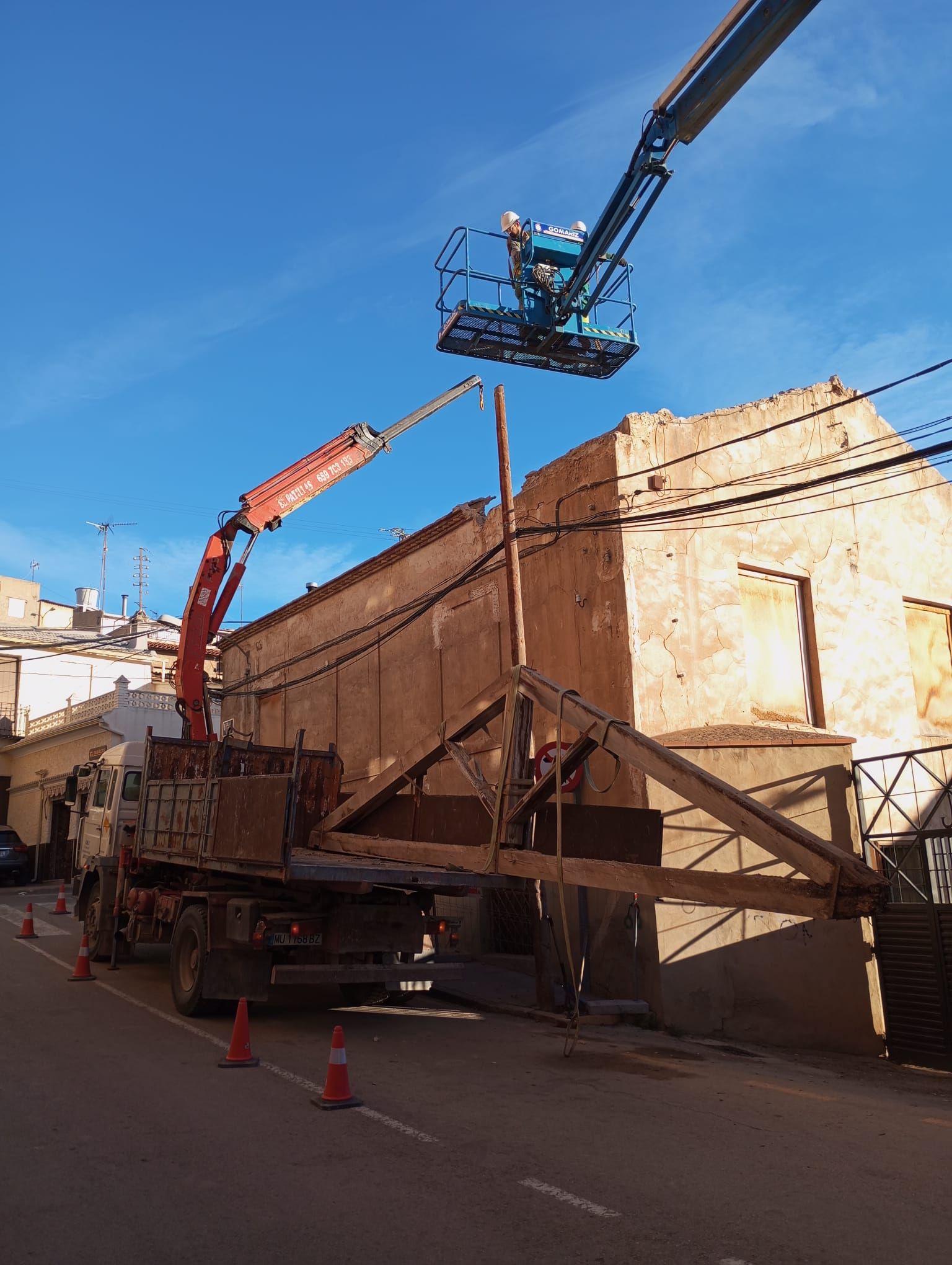 Una grúa está levantando una estructura de madera delante de un edificio.