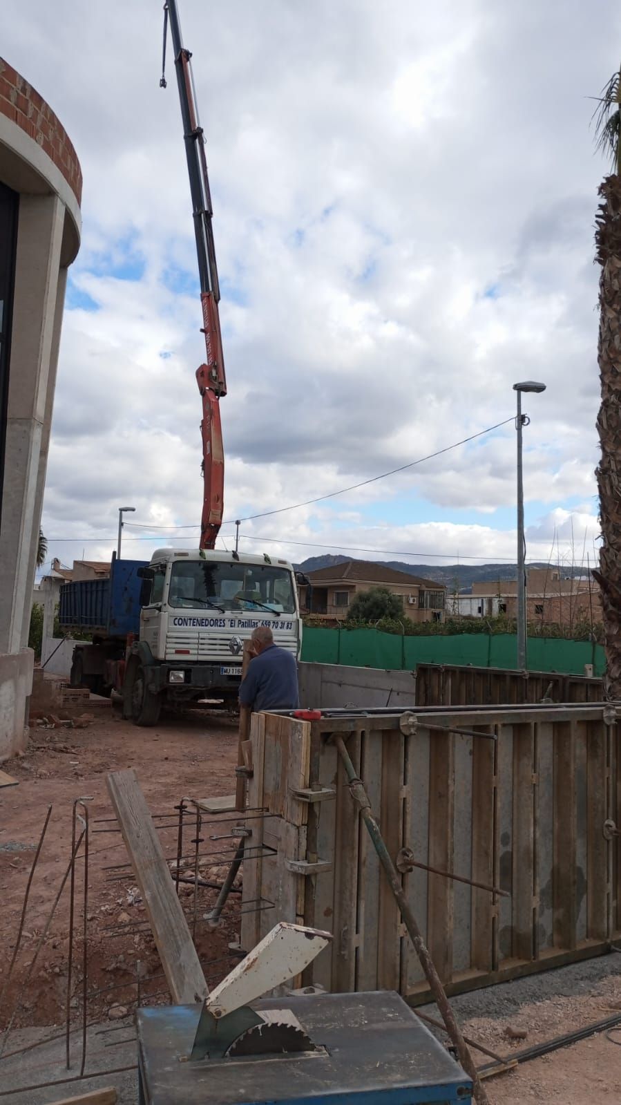 Un hombre está de pie junto a una grúa en un sitio de construcción.