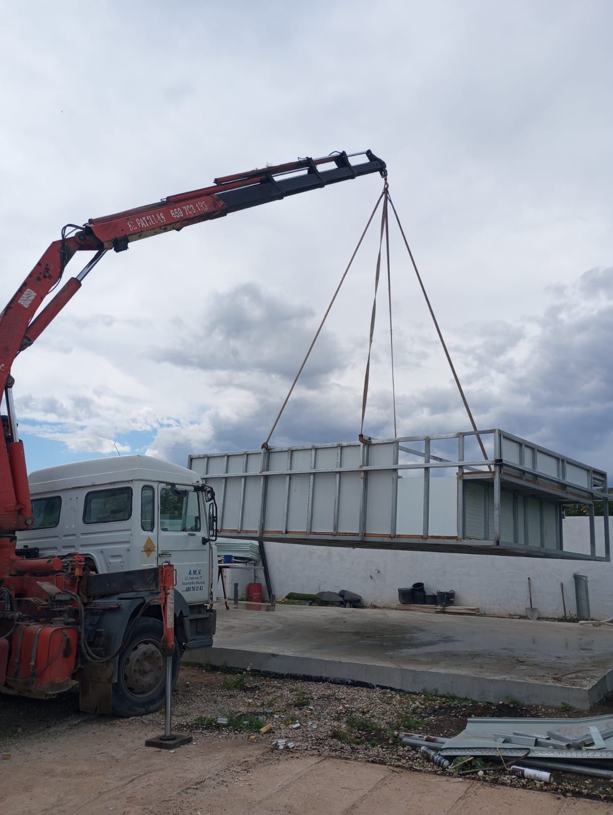Una grúa roja está levantando un gran edificio blanco.