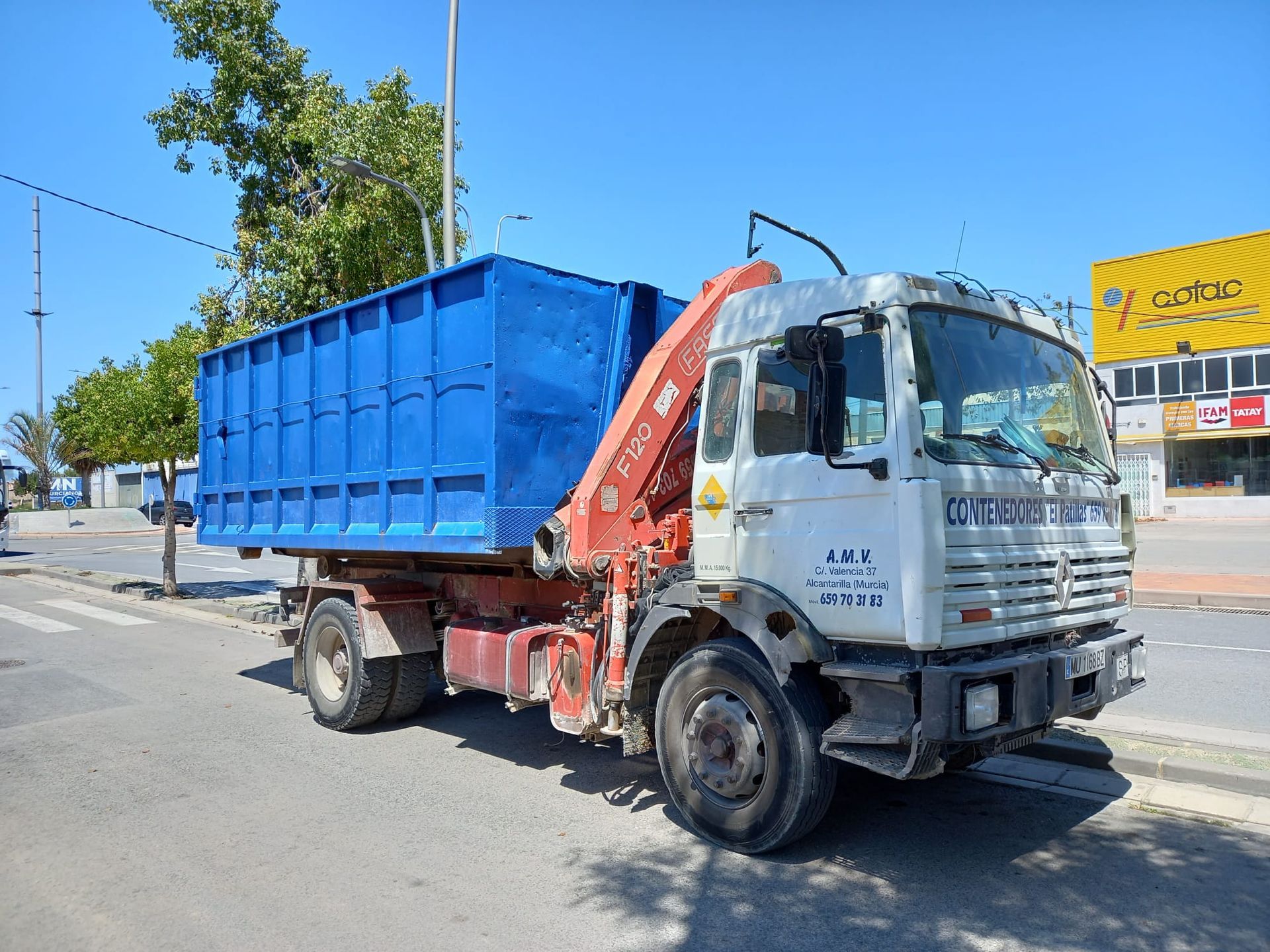 Un camión volquete azul está estacionado al costado de la carretera.