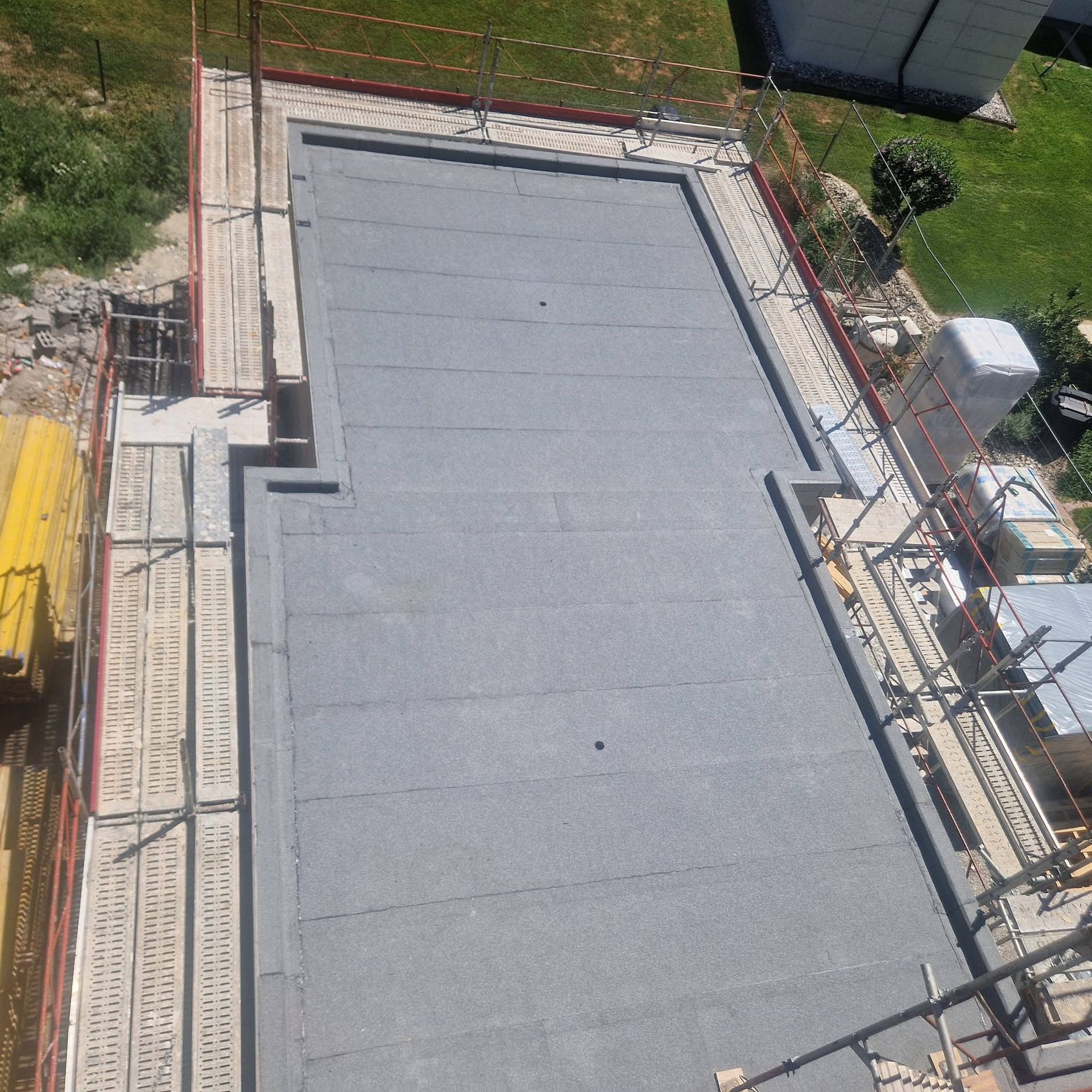 Toit en bardeaux gris avec une cheminée blanche centrale sous un ciel bleu