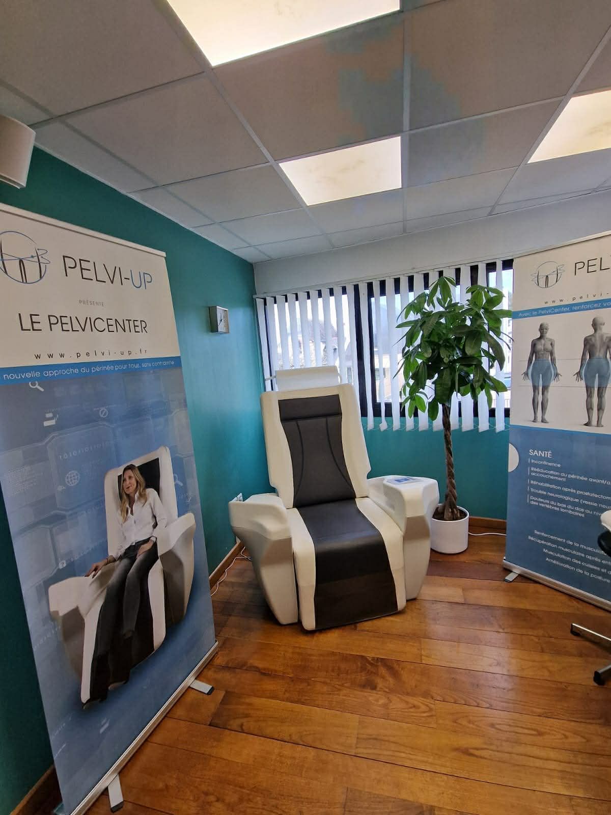 Un fauteuil thérapeutique spécialisé pour le traitement du plancher pelvien est installé dans une pièce, entre deux bannières informatives de marques différentes.