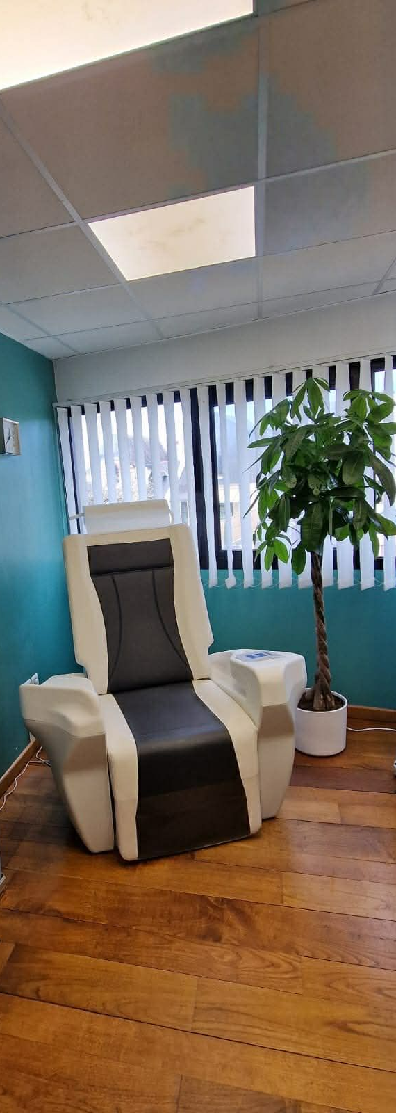 Dans un cabinet médical, un fauteuil spécialisé pour la rééducation périnéale est installé entre deux bannières publicitaires de marques différentes.