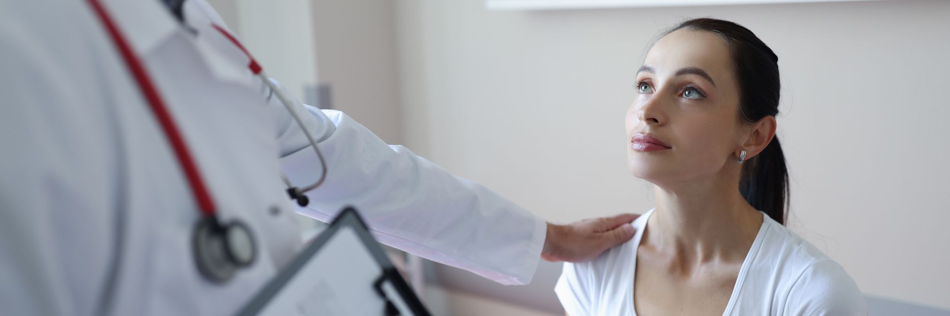 Lors d'une consultation, un médecin en blouse blanche, muni d'un stéthoscope, pose la main sur l'épaule d'un patient.