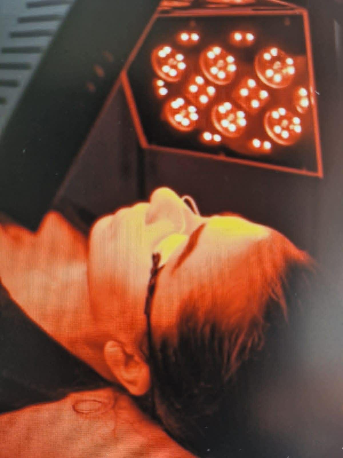 Personne allongée sur le côté sous une lumière orange chaude, regardant un projecteur de scène circulaire.