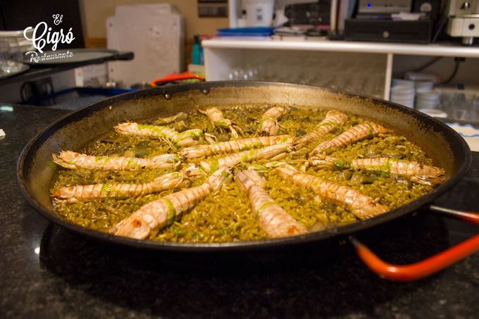 Una sartén grande con gambas cocinándose a fuego lento en aceite condimentado sobre los fogones
