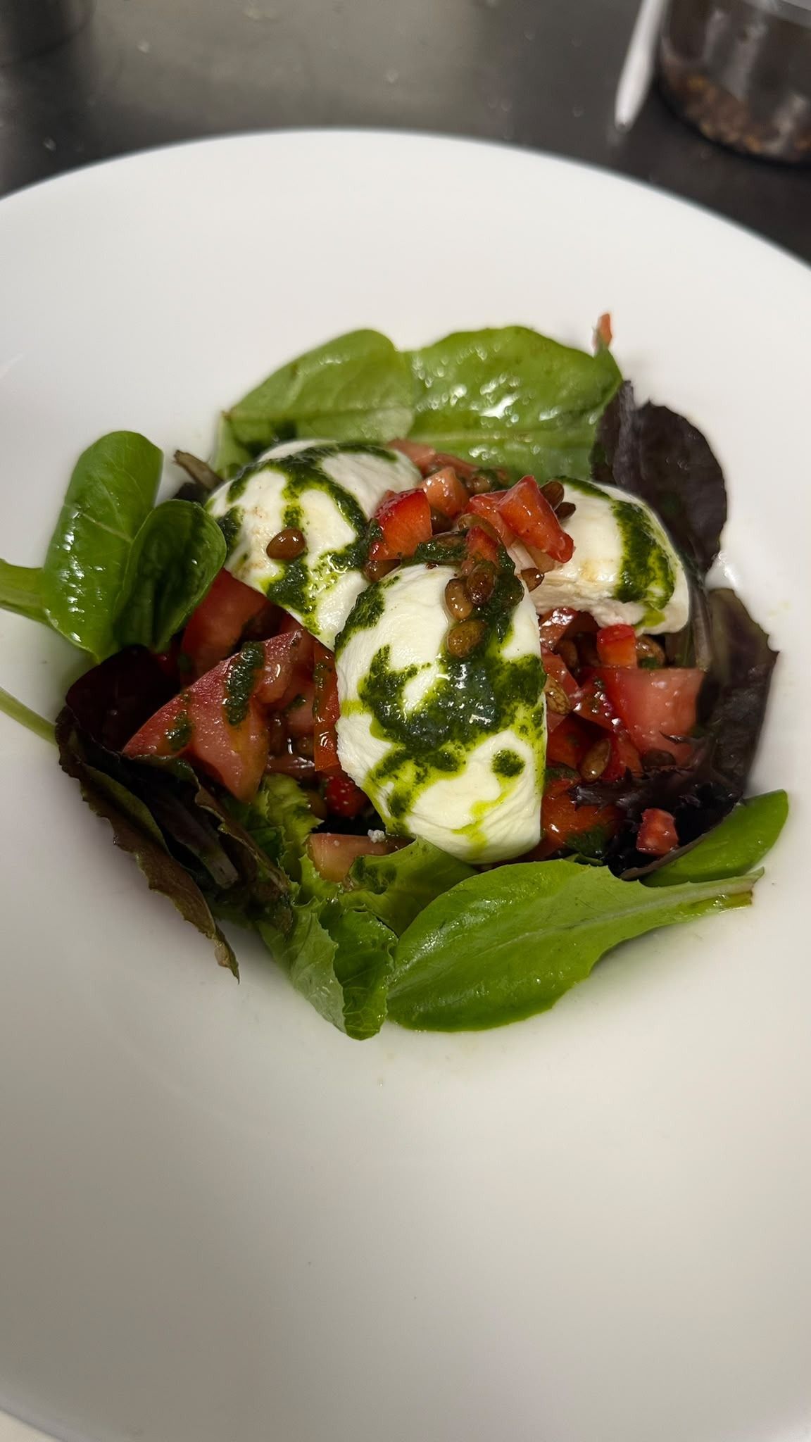Ensalada colorida con hojas verdes, tomates y aderezo cremoso en un plato blanco