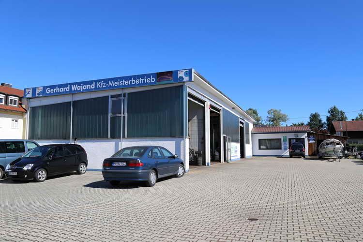 Eine Autowerkstatt mit einem davor geparkten blauen Auto. Auf dem Schild steht „Bernd Wojand Kfz-Meisterbetrieb“.