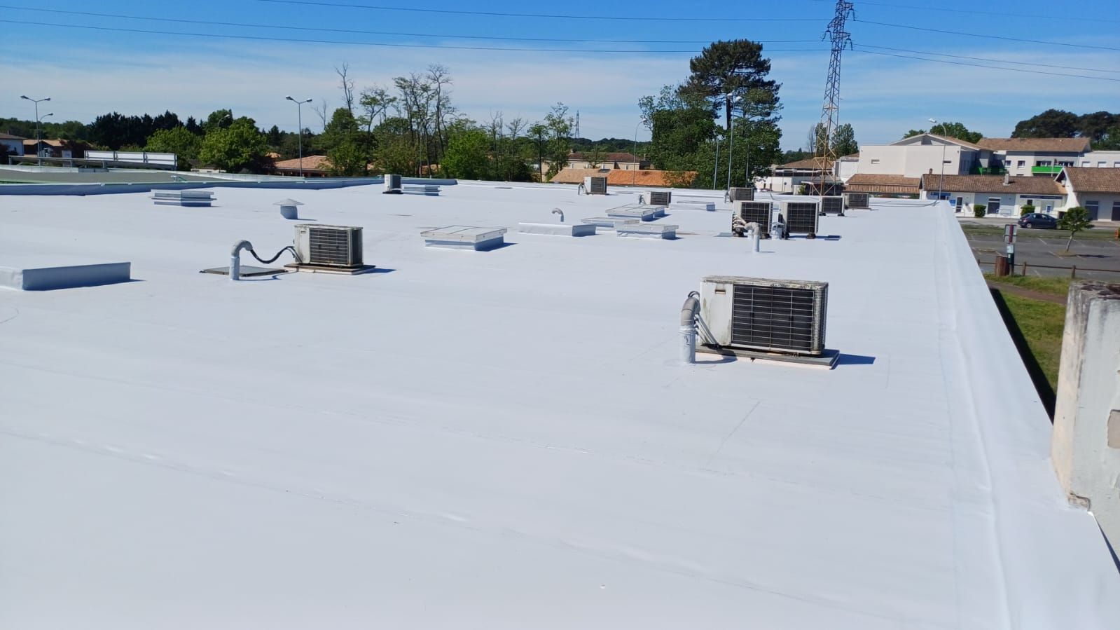 Un toit plat recouvert d'un matériau de toiture sombre et granuleux, entouré d'une bordure métallique.