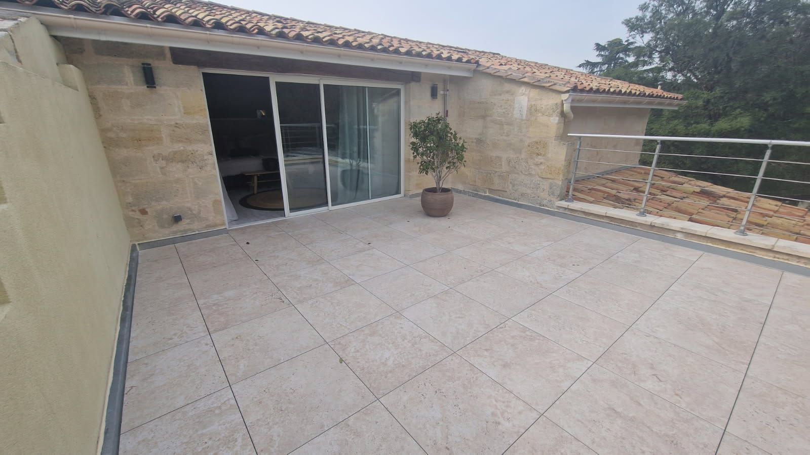 Un ouvrier vêtu d'une combinaison de protection sombre se tient sur un toit de tuiles.