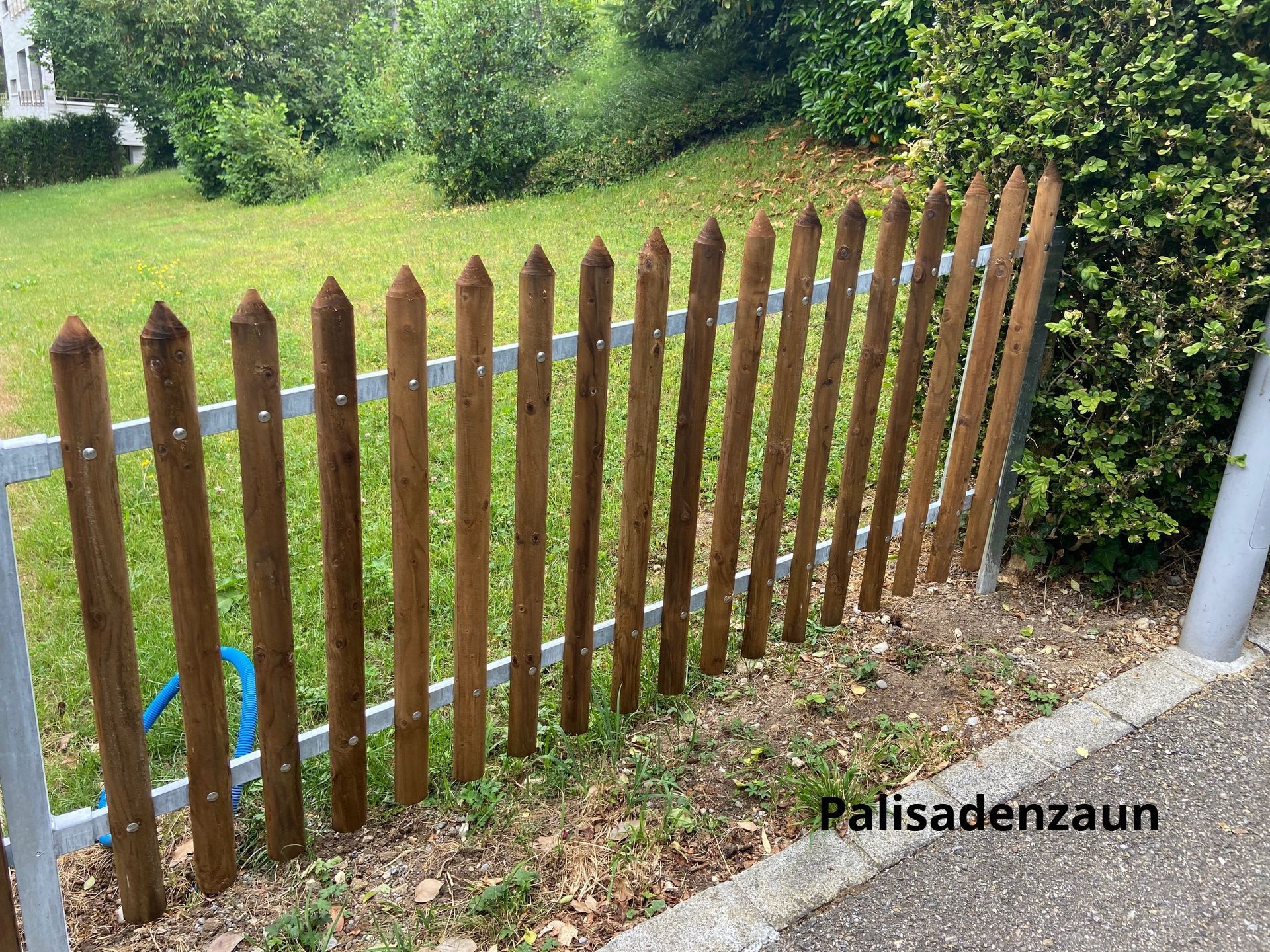 Ein hölzerner Lattenzaun umgibt ein üppiges grünes Feld.