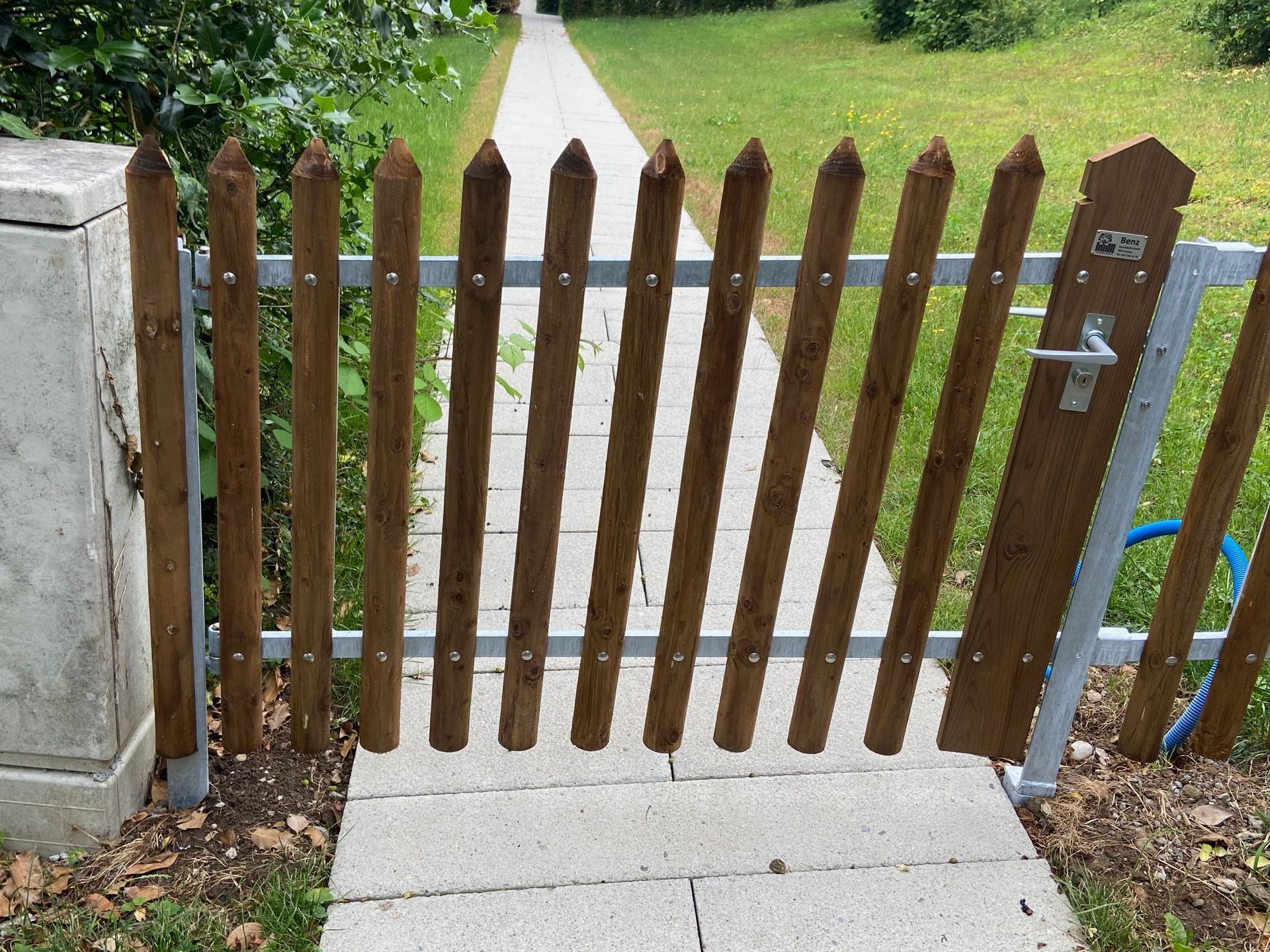 Ein Holzzaun ist zu einem Gehweg hin offen