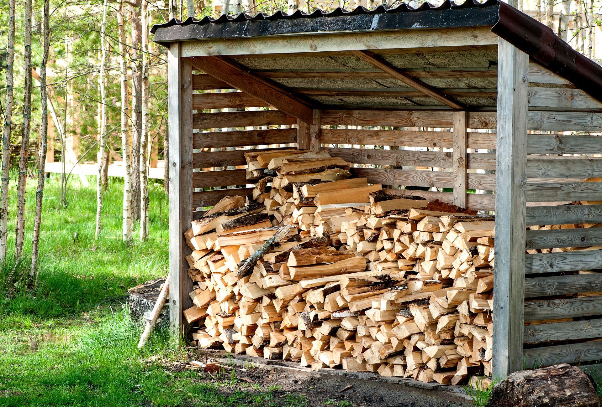 Pile de bois de chauffage sous un abri ouvert.