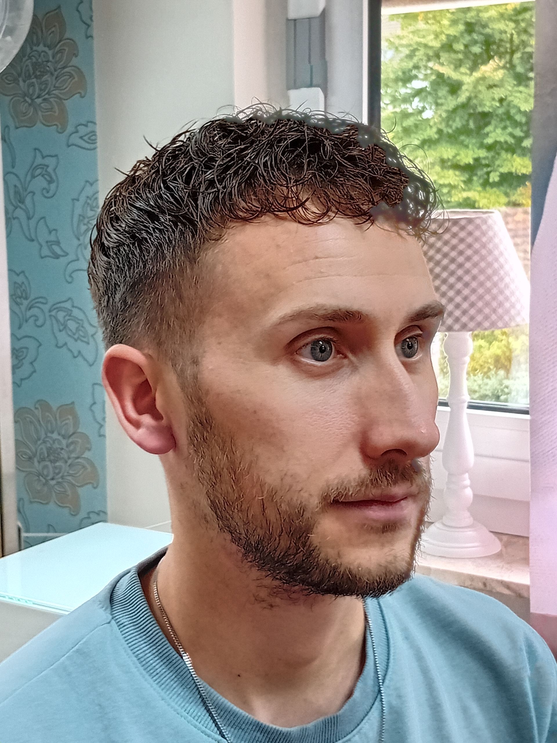 Moderner Herrenhaarschnitt mit kurzem Fade und lockigem Oberkopf