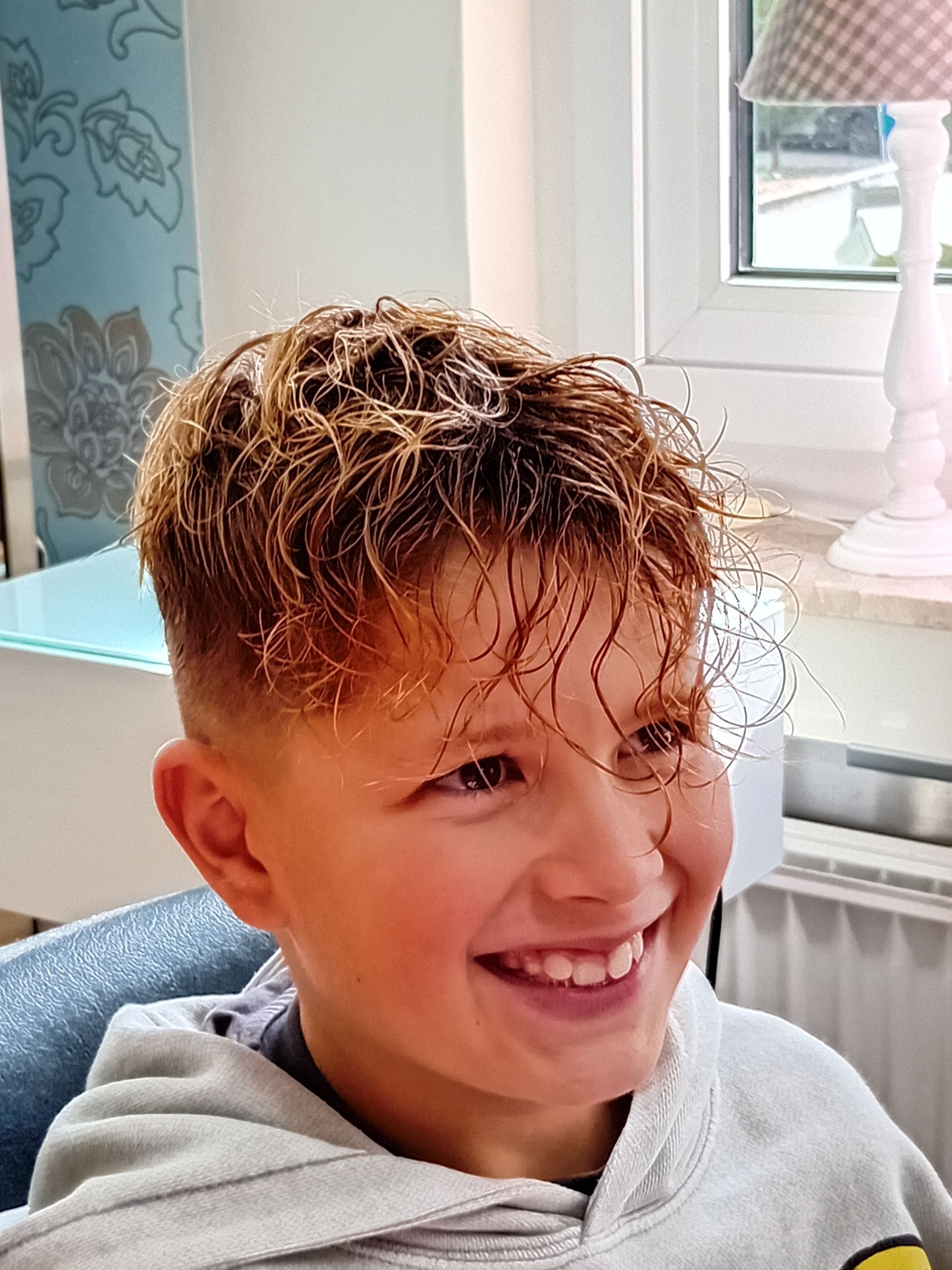 Trendiger Jungenhaarschnitt mit lockigem Oberkopf und frischem Styling