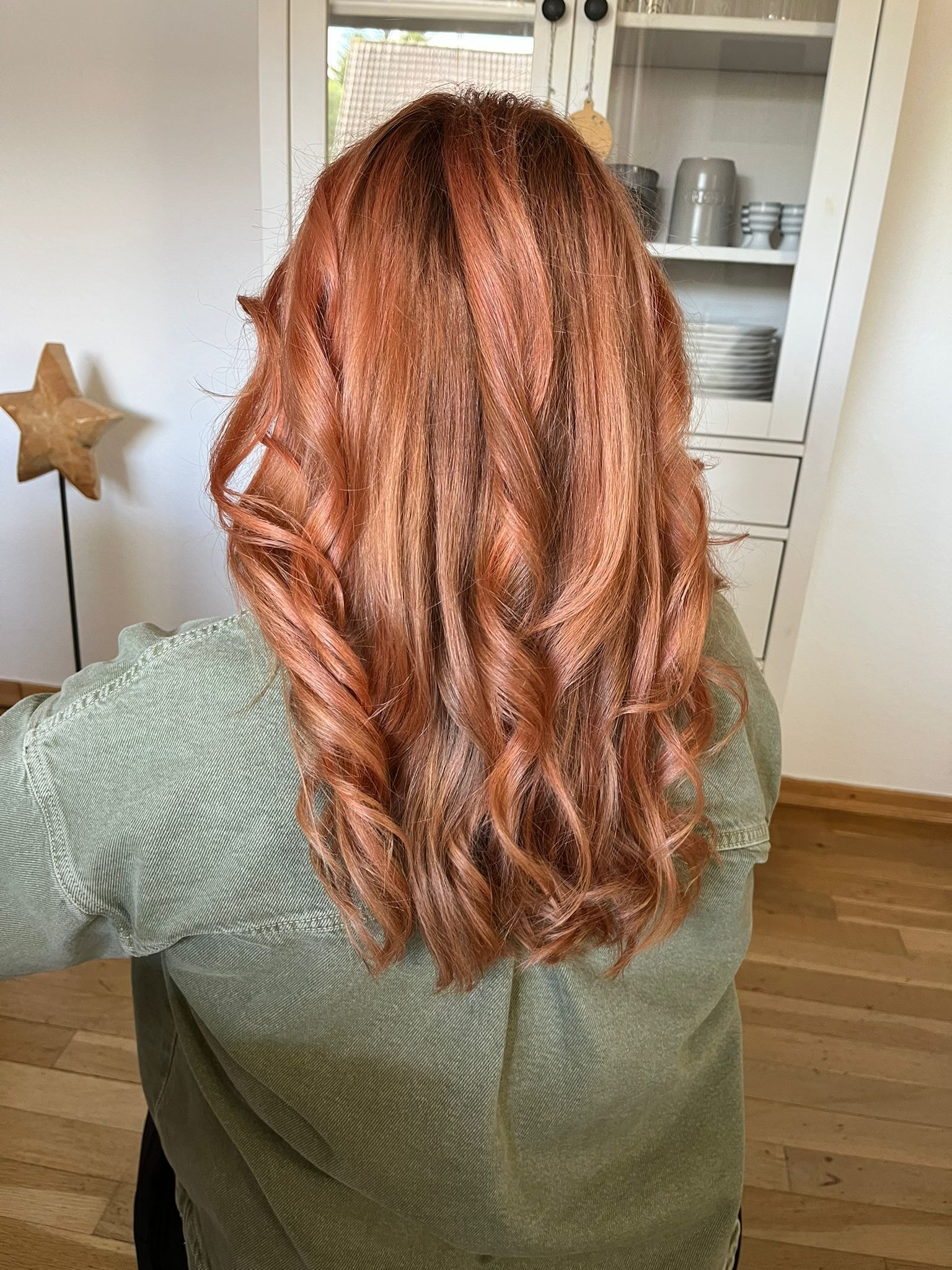 Kupferrote Lockenfrisur mit glänzender Coloration