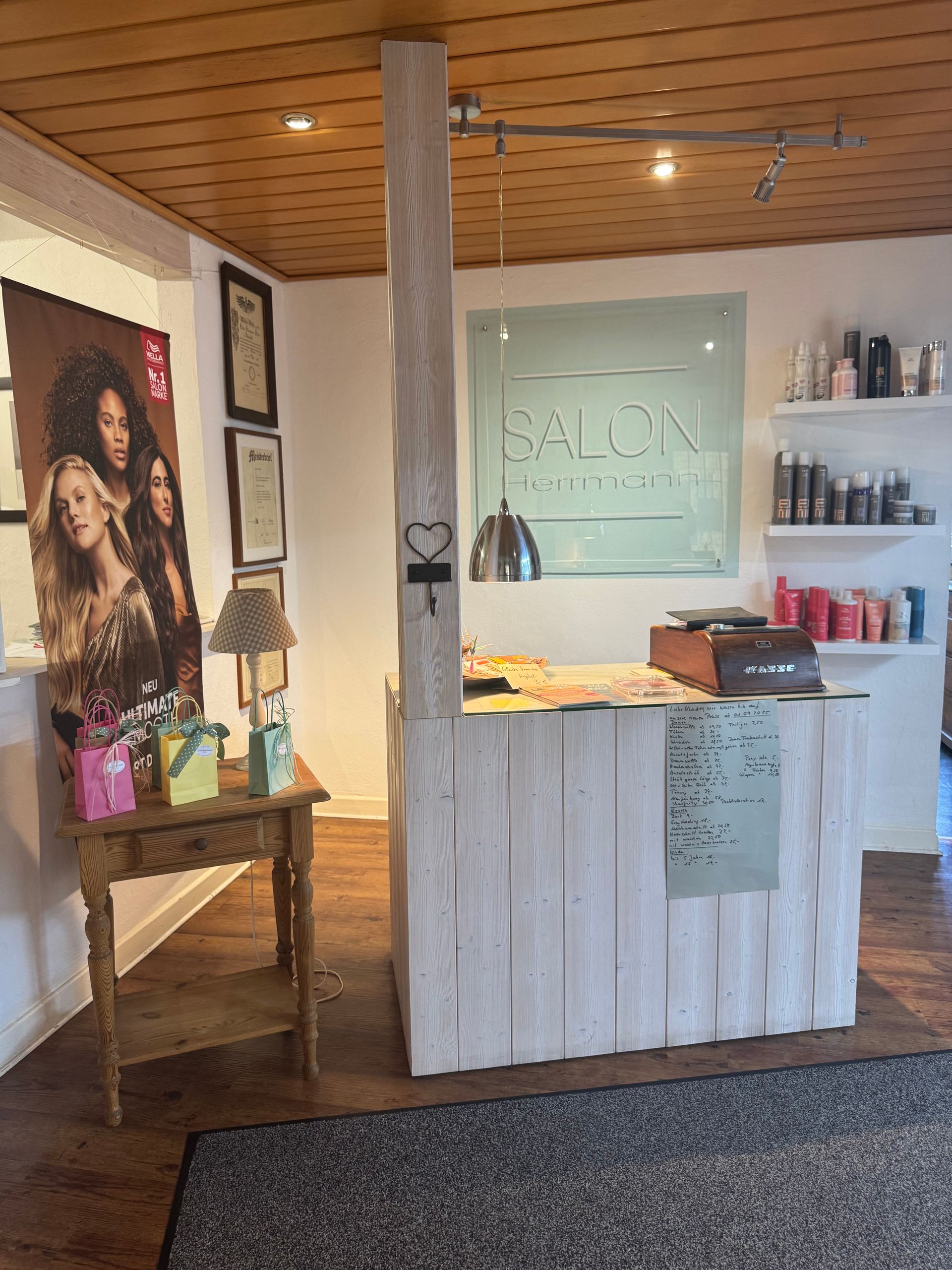 Saloneinrichtung mit einem weißen Empfangstresen aus Holz und einem Poster mit Models.